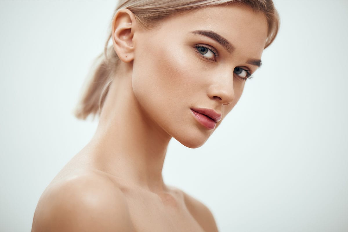 a woman looking at the camera with her chin tilted down after getting rhinoplasty in Naples.
