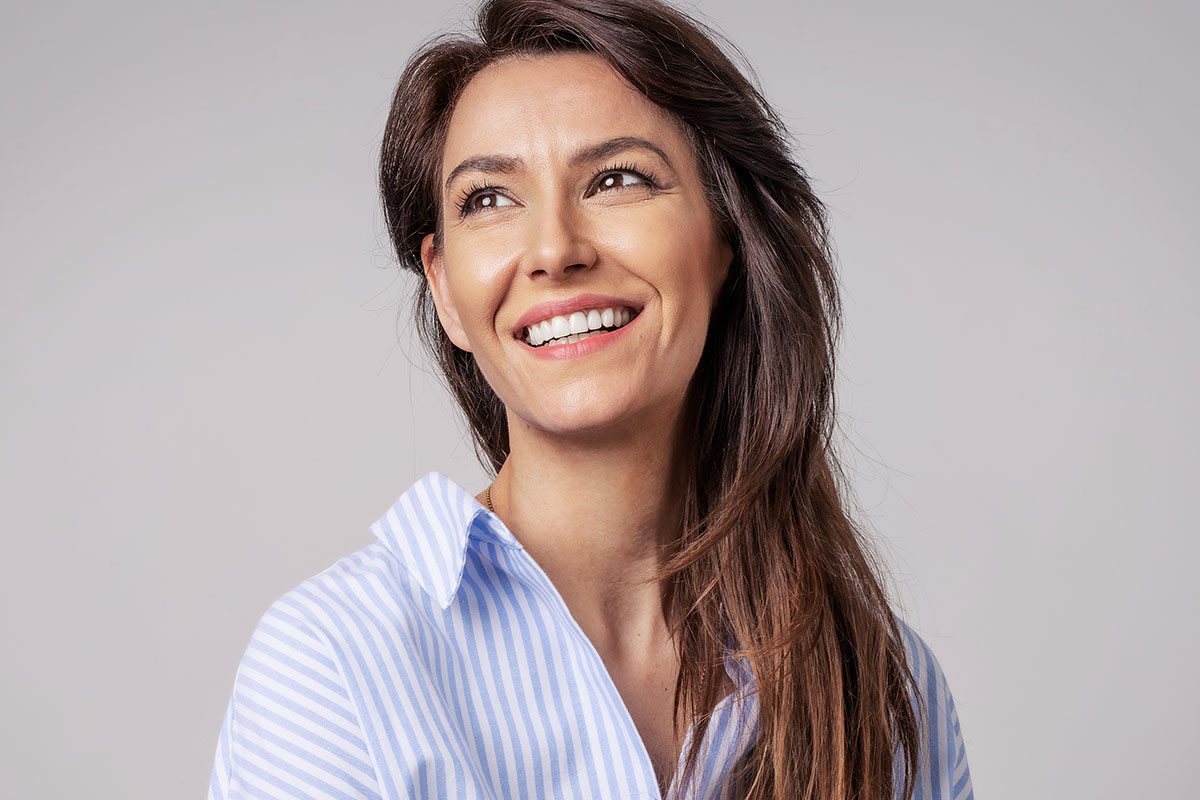 A middle aged woman smiling after getting dermal fillers in Naples.